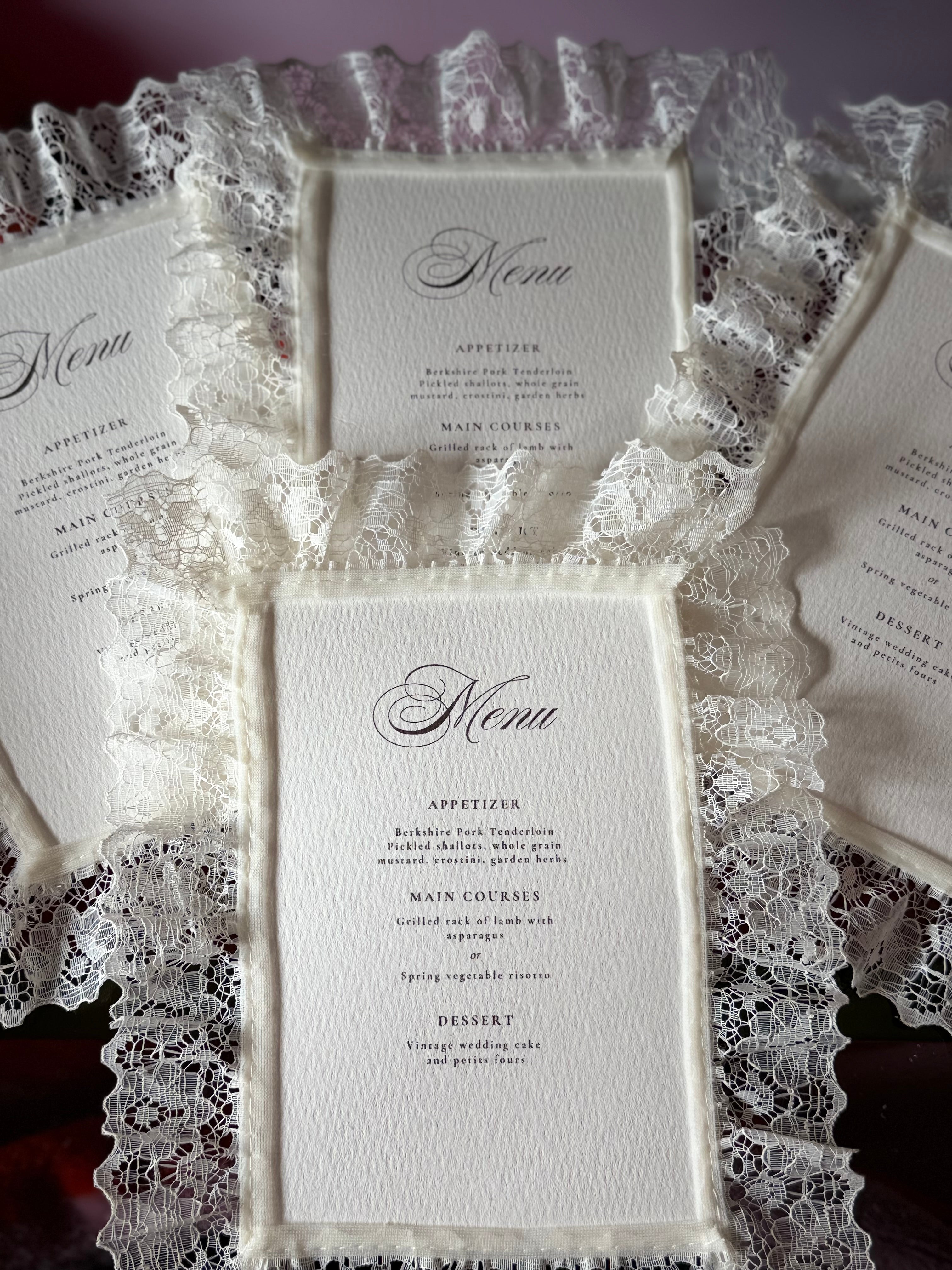 Lace-trimmed wedding menu on gold rimmed charger plate