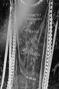 Lace-trimmed hanging wedding sign suspended from a tree, black and white