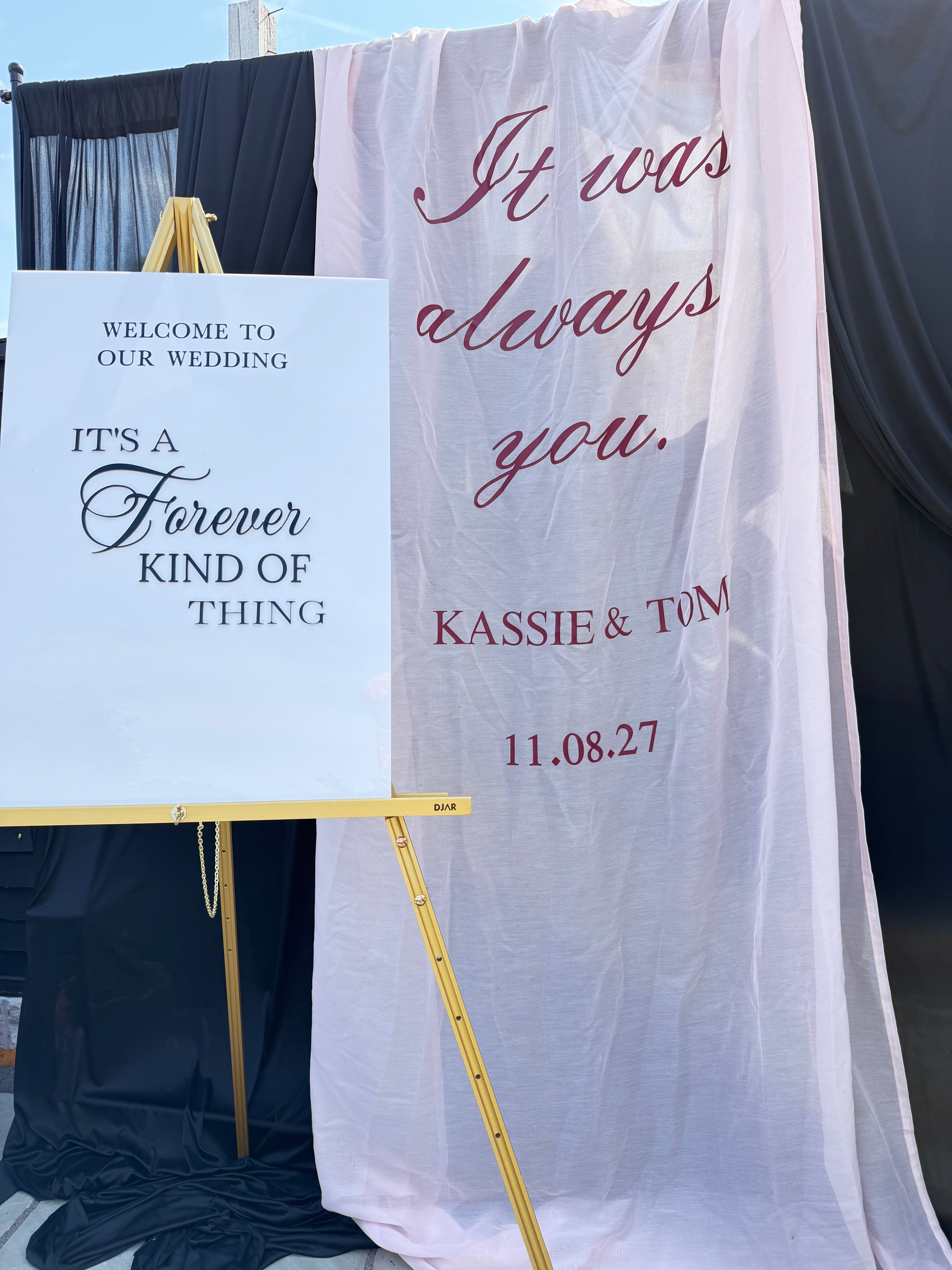 Personalised fabric wedding welcome sign draped alongside acrylic signage